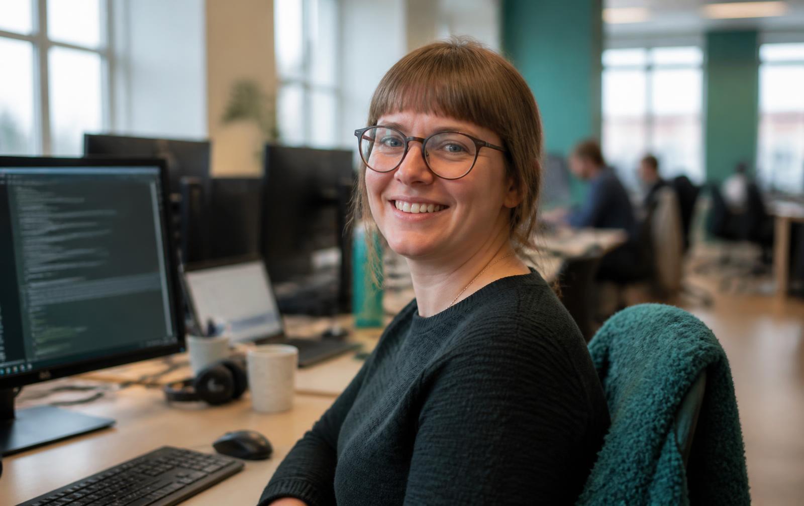 Smilende rådgiver ved arbeidsplassen sin i et lyst kontor
